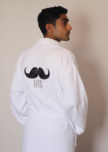 تحميل الصورة في عارض المعرض ، Man wearing white bathrobe with icon of mustache on its back and &quot;his&quot; written under it. He has both his hands in his pockets. Egyptian Cotton bathrobe. 